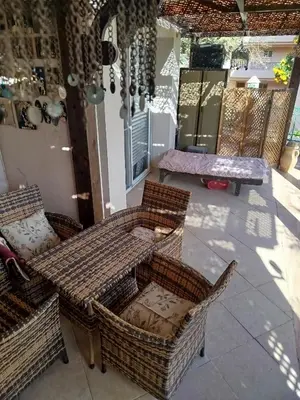 a patio with wicker chairs and a table and benches at Apartment with garden in sahl hasheesh in Hurghada