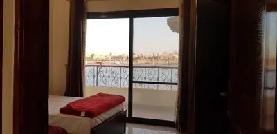 a room with a balcony with a bed and a window at El BOB HOUSE in Luxor