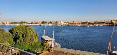 a boat is docked in a large river at El BOB HOUSE in Luxor