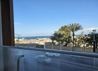 a window with a view of a beach and palm trees at Hurghada luxury apartment sea view 5 in Hurghada
