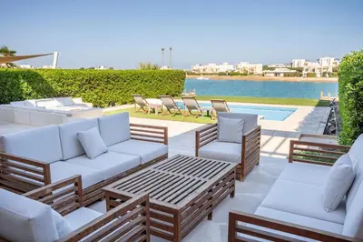 a patio with couches and chairs next to a pool at The Charming Beach Front Villa At Fanadir Bay W Private Pool in Hurghada