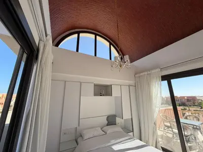 a bedroom with a bed and a large window at Bright Kamaran 2BR | Lofty Ceilings & Pool Access in Hurghada