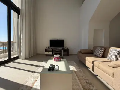 a living room with a couch and a tv at Bright Kamaran 2BR | Lofty Ceilings & Pool Access in Hurghada