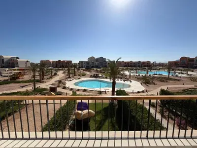 a view of a pool from a balcony of a resort at Bright Kamaran 2BR | Lofty Ceilings & Pool Access in Hurghada