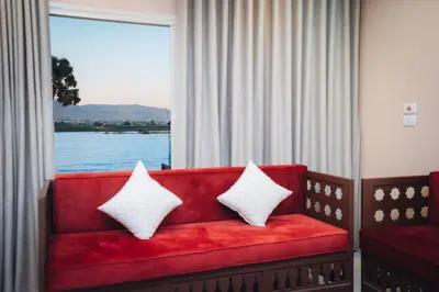 a red couch with two pillows sitting in front of a window at Karnak Temple Inn in Luxor