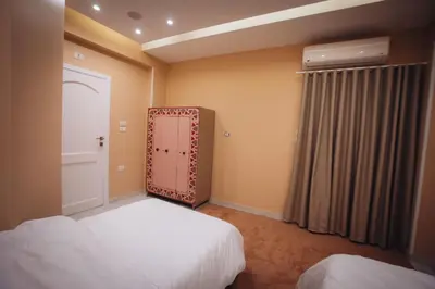 a bedroom with two beds and a door with a window at Karnak Temple Inn in Luxor