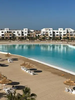 a large swimming pool with chairs and umbrellas at 4BR Penthouse, Lagoon View, Swanlake El Gouna in Hurghada