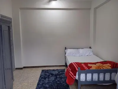 a bedroom with a bed with a red blanket on it at Rafe Guest House in Luxor