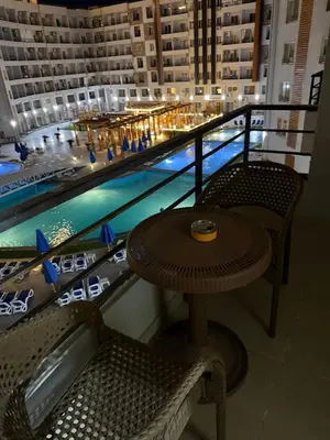 a table and chairs next to a swimming pool at Tiba Golden Beach Hurghada in Hurghada