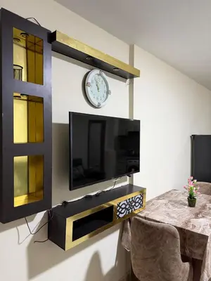 a tv on a wall with a clock and a table at Tiba Golden Beach Hurghada in Hurghada