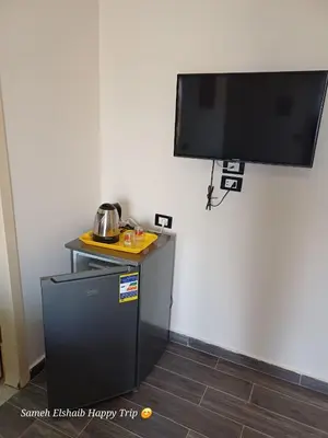 a tv hanging on a wall with a small refrigerator at Suncare America in Hurghada