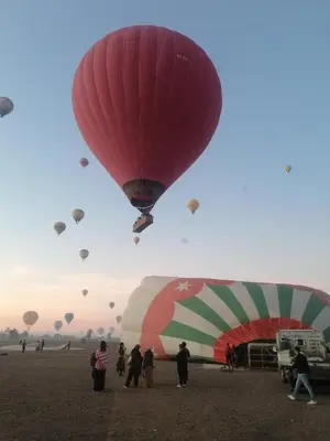a group of people flying kites in a field at Moonlight in Al Aqālitah