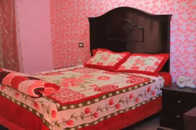 a bedroom with a bed with red and white blankets and pillows at Moonlight in Al Aqālitah