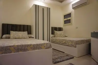 a small bedroom with two beds and a window at Seaview Classy 2Bedroom Suite with beach access in Hurghada