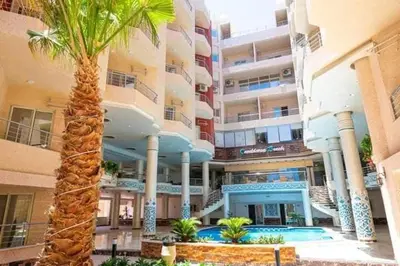 a large building with a palm tree in front of it at Seaview Classy 2Bedroom Suite with beach access in Hurghada