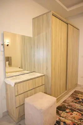 a bathroom with wooden cabinets and a stool and a mirror at 4,5 Zimmer Kiteapartment Selena Bay in Hurghada