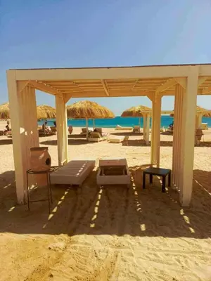 a pavilion on the beach with chairs and umbrellas at Sunrise Luxury Apartment in Hurghada