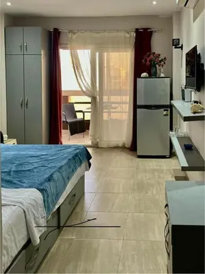 a bedroom with a bed and a kitchen with a refrigerator at Studio Mirage Bay in Hurghada