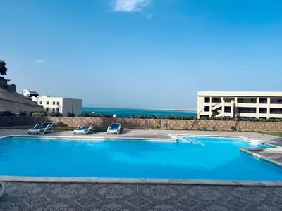 a swimming pool with two chairs and a building at Sea View luxury chalet in Hurghada