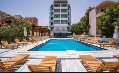 a swimming pool with lounge chairs and a building at Tartils Beach Resort Al-Ahyaa in Hurghada