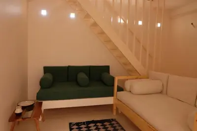 a living room with a green couch and stairs at Mountian View Domes in Al Aqālitah