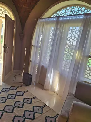a living room with curtains and a television in front of a window at Mountian View Domes in Al Aqālitah