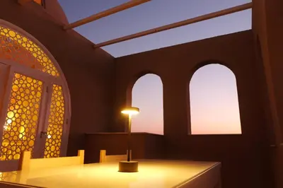 a room with three windows and a light on a table at Mountian View Domes in Al Aqālitah