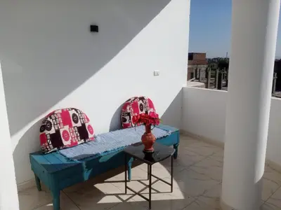 a room with two chairs and a table with a vase at Bait el gabal in Al Aqālitah