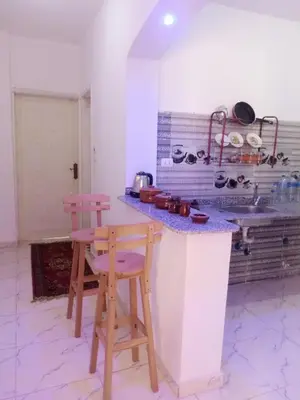 a kitchen with two chairs and a counter with a sink at Bait el gabal in Al Aqālitah