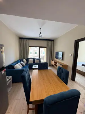 a living room with a wooden table and blue chairs at Casa Bonita 2307 in Hurghada
