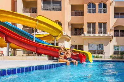a man and a woman sitting on a slide in a pool at Contenintal Rosa Boho Aquapark Hotel 3 Stars in Hurghada