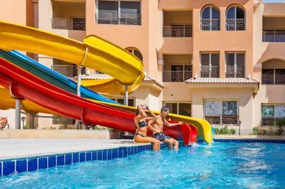 a man and a woman sitting on a slide in a pool at Contenintal Rosa Boho Aquapark Hotel 3 Stars in Hurghada