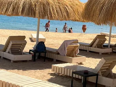 a beach with chairs and umbrellas and people on the beach at rezort Al Hambra, rezort Princess in Hurghada