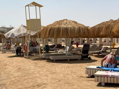 a beach with chaise lounges and straw umbrellas on the sand at rezort Al Hambra, rezort Princess in Hurghada