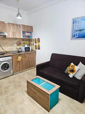 a living room with a black couch and a kitchen at Sheraton Plaza 319 in Hurghada