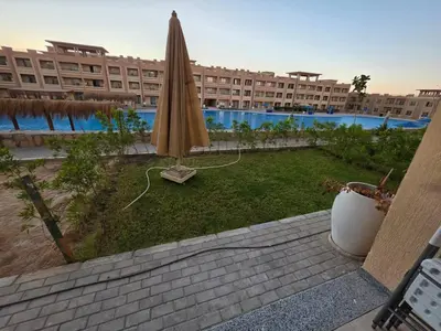 a patio with an umbrella and a large building at Cozy Fully Furnished Apartment in Hurghada