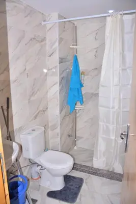 a bathroom with a toilet and a shower with a blue towel at Mirage Bay Resort Aquapark Cap Ahmed Suite in Hurghada