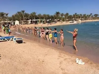 a group of people walking on the beach at Mirage Bay Resort Aquapark Cap Ahmed Suite in Hurghada