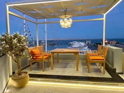a dining table and chairs on a balcony with a boat at مارينا الغردقه in Hurghada
