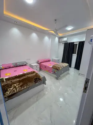 two beds in a room with marble floors at شقه لك ب الكامل فندقي in Safaga
