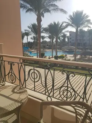 a balcony with a view of a pool and palm trees at Sunset Barrel in Hurghada