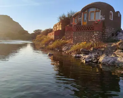 a house sitting on the side of a river at ASSINGAR Island in Aswan
