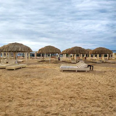 a group of straw umbrellas and chairs on a beach at البرنسيسة in Hurghada