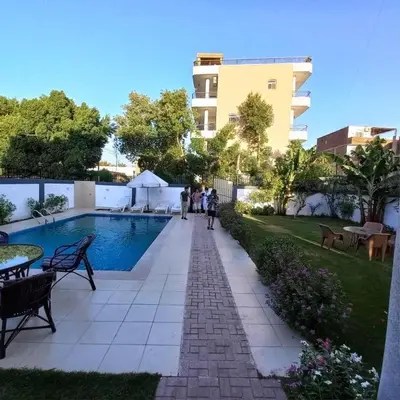 a group of people walking down a sidewalk next to a pool at Entire Oasis Villa - Heart of Ancient Luxor in Luxor