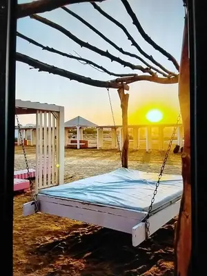 a swing bed in the sand with the sunset in the background at Hurghada Pool & See View Studio in Hurghada