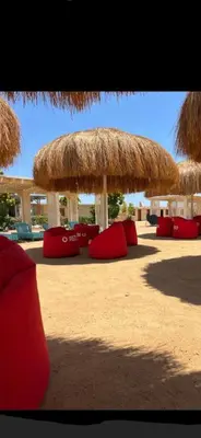a resort with red chairs and a straw umbrella at Hurghada Pool & See View Studio in Hurghada