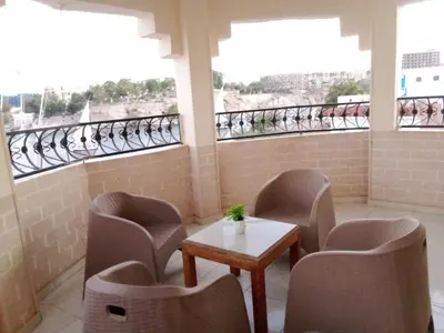 a room with chairs and a table and windows at D Guest house in Nag` el-Ramla