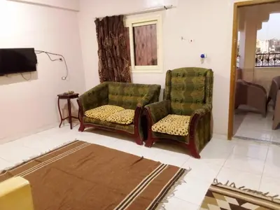 a living room with two chairs and a tv at D Guest house in Nag` el-Ramla