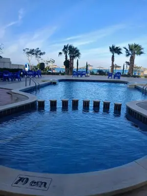 a swimming pool with blue water and palm trees at شقه بمنتجع كذابلانكا in Hurghada