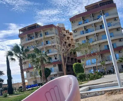 a pink chair on the beach in front of a building at شقه بمنتجع كذابلانكا in Hurghada